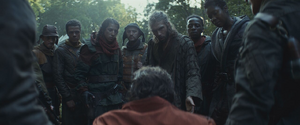 Seven members of the Maya Pei Brigade, including Snee, stand over a bound Cassian Andor on Yavin 4 with two other brigade members flanking the prisoner.
