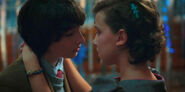 Mike and Eleven dance together in the Snow Ball and lean for a kiss.