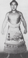 Kyushuzan poses with his kesho-mawashi