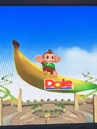 Screenshot of AiAi waving as the big banana carries him away