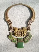 Redemption Island A necklace of a set of golden faces with designs and jade stones.