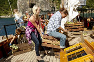 Andrea pulls a crate from under Malcolm.