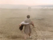 The Doctor carries Peri to safety.