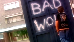 A  spray paints "" graffiti on the side of . (:  [+]Russell T Davies, Doctor Who series 1 (BBC One, 2005)