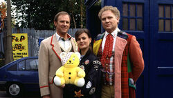 Pudsey with Peter Davison (the Fifth Doctor), Sophie Aldred (Ace) and Colin Baker (the Sixth Doctor) on the set of TV: Dimensions in Time.