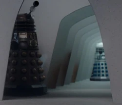 Within the Dalek City, a bronze Dalek and a silver Dalek sport the same refined fender model