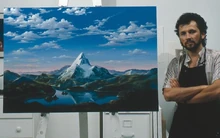 Artist Dario Campanile poses with a picture Paramount commissioned him in 1986 to paint for its 75th anniversary. The company later used the painting as a basis for its new logo. That logo was introduced as a prototype in the 1986 film ; the 1987 film  are both the first to feature the finalized version of the logo. 1999's  was the first to use an enhanced version of the logo, which was last used on 2002's .