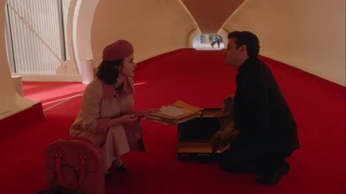 Midge helps Lenny with his fallen legal documents inside JFK airport.