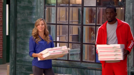 Kate enters the studio with pizza.