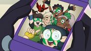 A scroll showing a photo of Willow, Hunter, Skara, Gus, Viney, and Flapjack. Except for Flapjack, they are all wearing green facepaint and green uniforms, Gus and Willow are wearing fingerless gloves, and Viney can be seen wearing elbow pads.