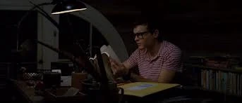 Ethan reading in his room with glasses on.