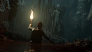 Rachel wading through bones in front of the statue of Pazuzu. Photo from the teaser.