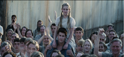 Prim, Gale, and Mrs. Everdeen in the crowd at the train station.