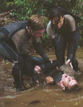 Katniss y Peeta metiendo a Finnick en agua luego de la niebla venenosa.