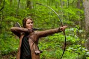 Katniss hunting in the woods with a bow and arrow.