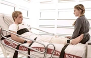 Peeta strapped to a hospital bed, speaking with Prim, in Mockingjay - Part 2.