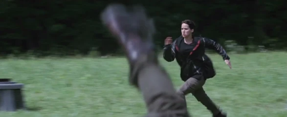 Glimmer stabs the District 6 female as Katniss begins running.