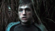 District 6 female morphling in camouflage mode hidden behind Peeta.