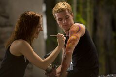 The District 6 female painting Peeta's arm in the Training Center.