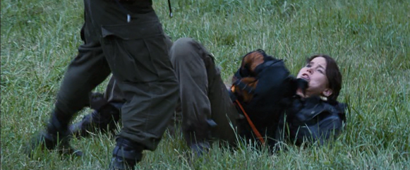 When Katniss trips, the District 9 male tries to chop her.