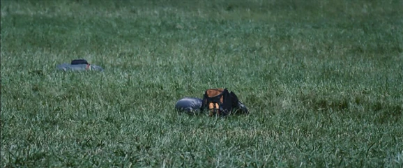 The orange backpack laying on the grass.