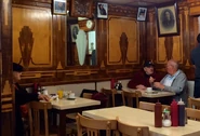 Interior of the café, with the two men seated on the right being the exact place the twins would sit every morning in the 1960s (with the unchanged wood paneling)