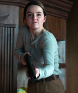 Abby uses a shotgun to cripple Joel.