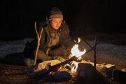 S1 E6 Ellie sitting at campfire