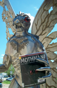 The Mothman Statue holding Jeff Wamsley's book