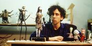 A picture of Tim Burton next to the puppet of Jack with all the other characters