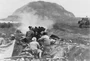 In the attack of the 28th Marines on the dominating height, a 37mm gun crew fires at caves at the foot of Suribachi suspected of holding Japanese gun positions.
