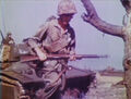 1 April 1945, L-Day on Okinawa. An infantry Marine moves across the beach under cover of an LVT(A)-4 amphibian tank. Still image from USMC motion picture film