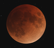 A lunar eclipse can be seen above, where the Earth is between the Sun and the Moon. The reddish hue of a lunar eclipse is due to the small amount of sunlight that is reflected from the Earth's nightside's atmosphere.