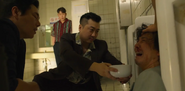 Hwang Jae-hun holds a bowl in front Seong Gi-hun in Season 1.