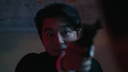 The Recruiter aiming his revolver towards Seong Gi-hun.