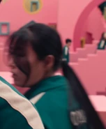 Player 028 walking past Jung-bae and Gi-hun.