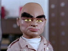 The Hood's eyes glowing yellow, staring right at the camera