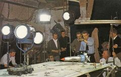 The crew prepare to film a scene. L-R (excluding Peter Wragg, who is standing on the planks above): electrician (name unknown); Ian Wingrove; John Howard; unknown person; Ted Cutlack; Derek Meddings; Garry Coxall; Harry Oakes (who is standing behind Coxall)