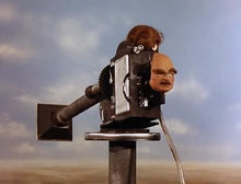 A mask and wig hanging from a camera with a long lens