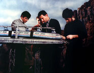 Nick Middleton (centre in background) standing behind Derek Meddings (who is in centre foreground) on the set of Brink Of Disaster