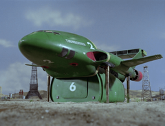 Thunderbird 2 in an oil field, half raised above the ground and exposing Pod 6 underneath