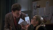 Vicki showing Knox invitations to Bruce Wayne's charity benefit.