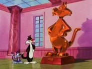 Sylvester shows his protege Furrball a statue of himself