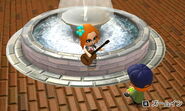 A female Mii playing the guitar on the fountain while her boyfriend listens,