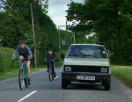 The Yugo is overtaken by cyclists.