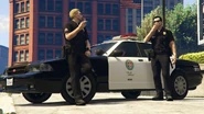 Two LAPD officers standing on a Crown victoria cruiser in 2021