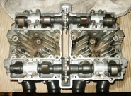 Overhead view of an air cooled cylinder head from a Suzuki GS550 showing dual camshafts, drive sprockets and cooling fins.