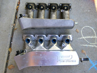 Comparison of a stock intake manifold for a Volkswagen  engine (top) to a custom-built one used in competition (bottom). In the custom-built manifold, the runners to the intake ports on the cylinder head are much wider and more gently tapered. This difference improves the volumetric efficiency of the engine's fuel/air intake.
