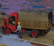 A red stakebed cargo lorry