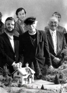 הכומר חובש כובע כרטיסן עם צוות ההפקה של העונה הראשונה